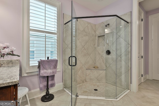 bathroom featuring tile patterned floors, vanity, a shower with shower door, and a wealth of natural light