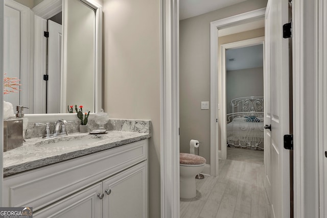 bathroom featuring wood-type flooring, vanity, and toilet