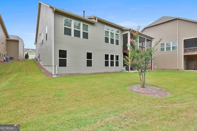 rear view of house featuring a lawn and central AC unit