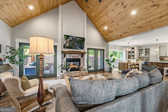 living room with wood-type flooring, high vaulted ceiling, a brick fireplace, wooden ceiling, and french doors