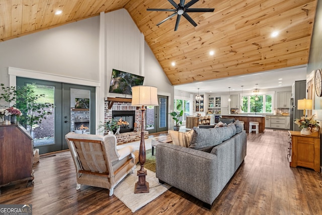 living room featuring wood ceiling, dark wood-type flooring, high vaulted ceiling, a fireplace, and ceiling fan