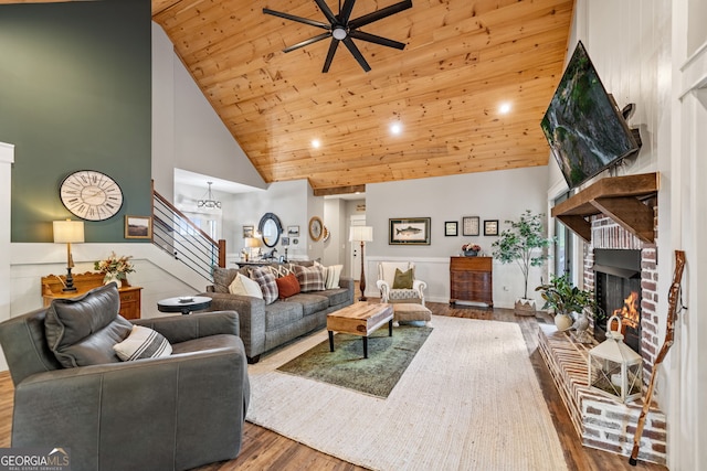 living room featuring hardwood / wood-style flooring, a fireplace, high vaulted ceiling, ceiling fan, and wooden ceiling