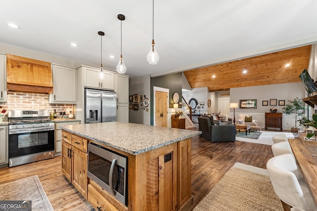 kitchen featuring white cabinetry, a kitchen island, pendant lighting, stainless steel appliances, and light hardwood / wood-style flooring