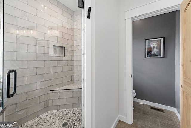 bathroom featuring tile patterned flooring, a shower with door, and toilet