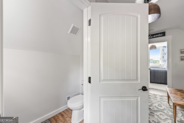 bathroom featuring hardwood / wood-style floors, lofted ceiling, and toilet