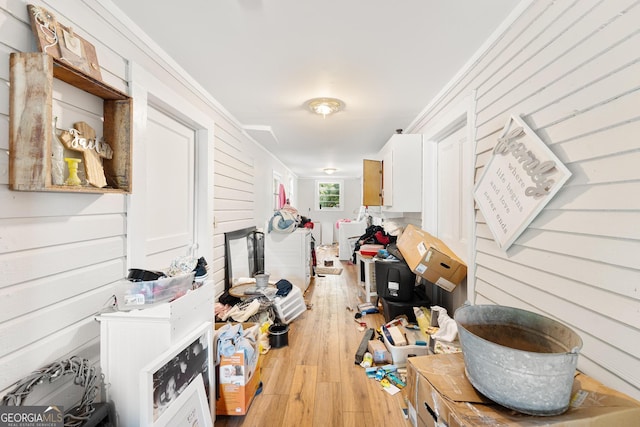 interior space featuring wooden walls, light hardwood / wood-style floors, and crown molding