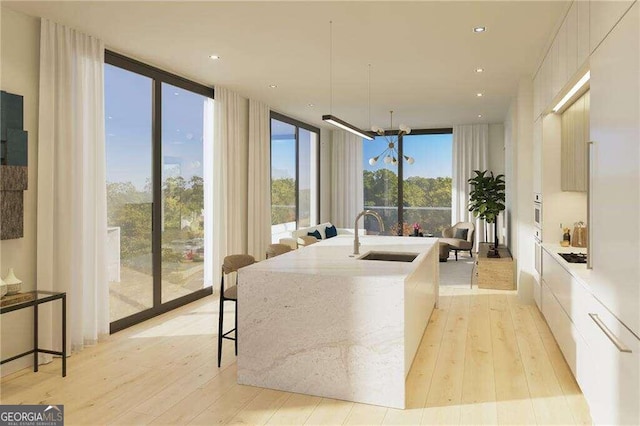 living room featuring light hardwood / wood-style floors, a wall of windows, and sink