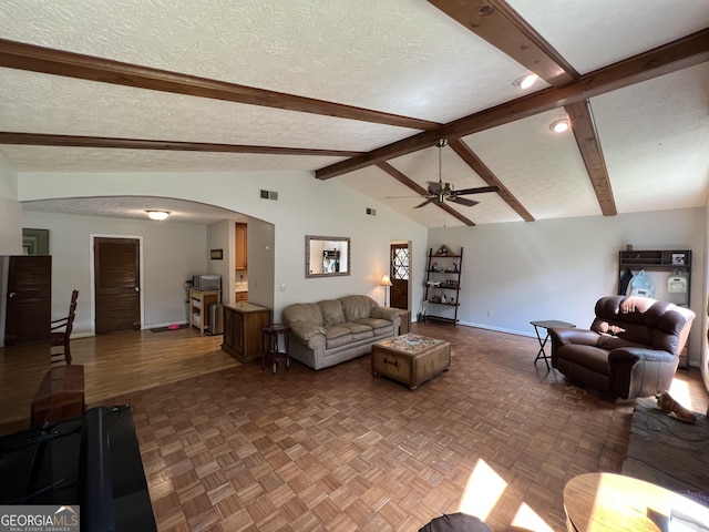 living room featuring visible vents, baseboards, arched walkways, a textured ceiling, and vaulted ceiling with beams