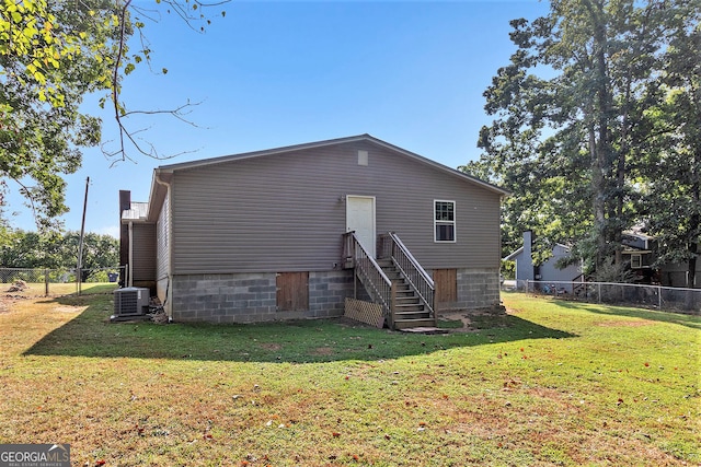 rear view of house featuring central air condition unit and a lawn