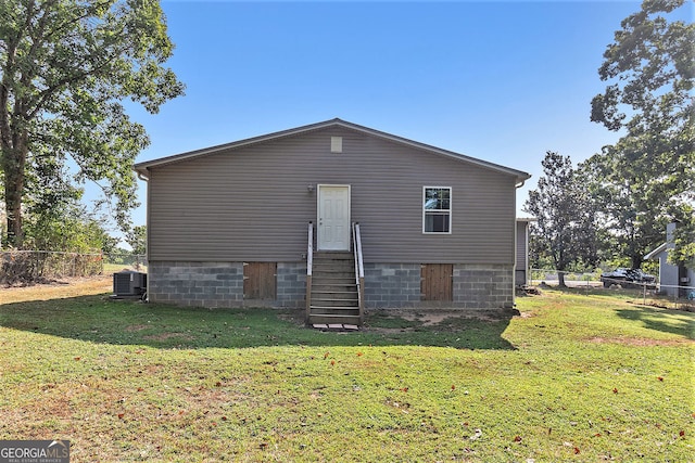 rear view of house featuring central AC unit and a lawn