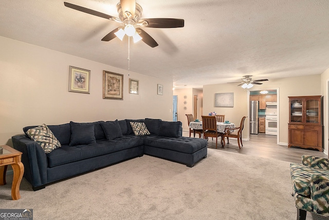 living room with ceiling fan, hardwood / wood-style floors, and a textured ceiling