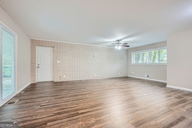 unfurnished room with ceiling fan, brick wall, and dark hardwood / wood-style flooring