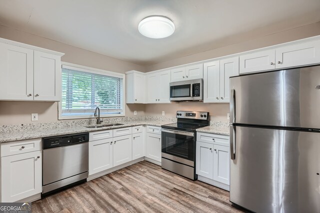 kitchen with white cabinets, light hardwood / wood-style floors, stainless steel appliances, and sink