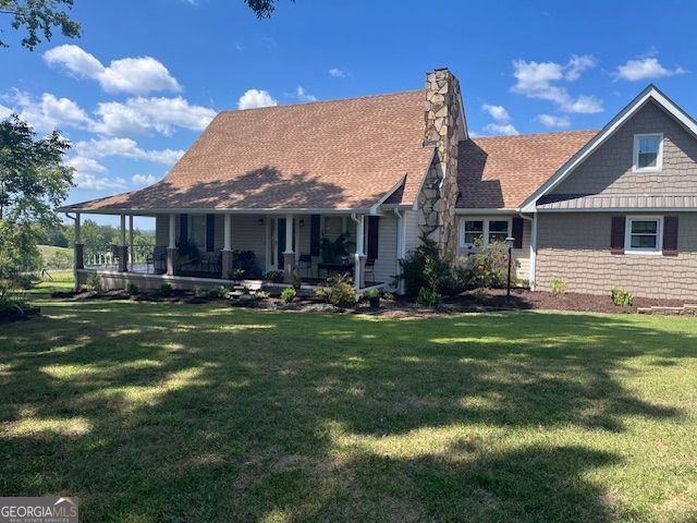 rear view of property featuring a lawn and covered porch