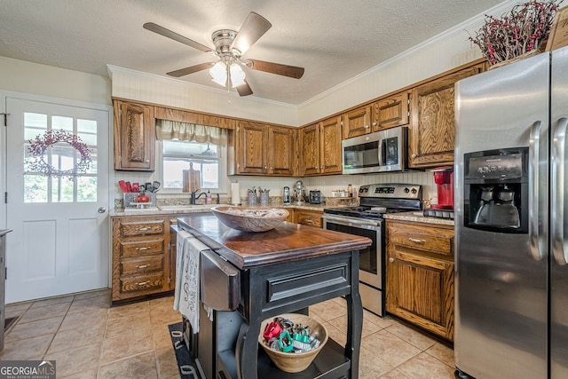 kitchen with butcher block counters, ceiling fan, appliances with stainless steel finishes, and crown molding