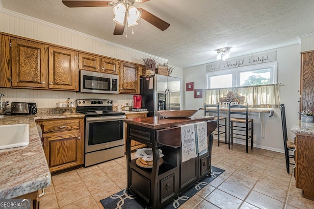 kitchen with a textured ceiling, ceiling fan, appliances with stainless steel finishes, and crown molding