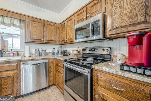 kitchen featuring light tile patterned floors, sink, ornamental molding, a textured ceiling, and stainless steel appliances