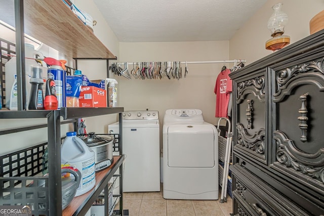 laundry area with a textured ceiling, light tile patterned floors, and washing machine and clothes dryer