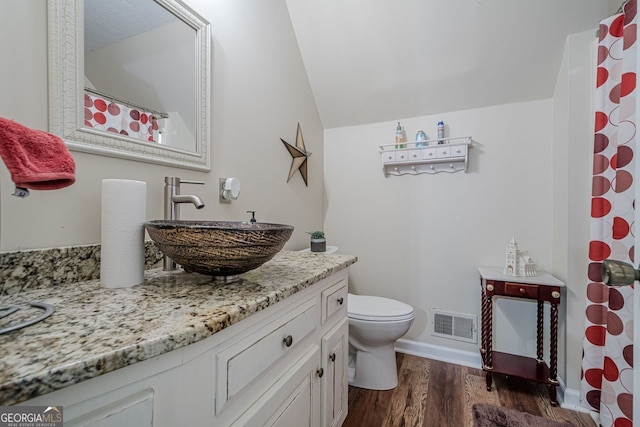 bathroom featuring vanity, hardwood / wood-style flooring, lofted ceiling, and toilet