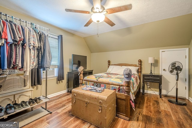 bedroom with wood-type flooring, lofted ceiling, ceiling fan, and a textured ceiling