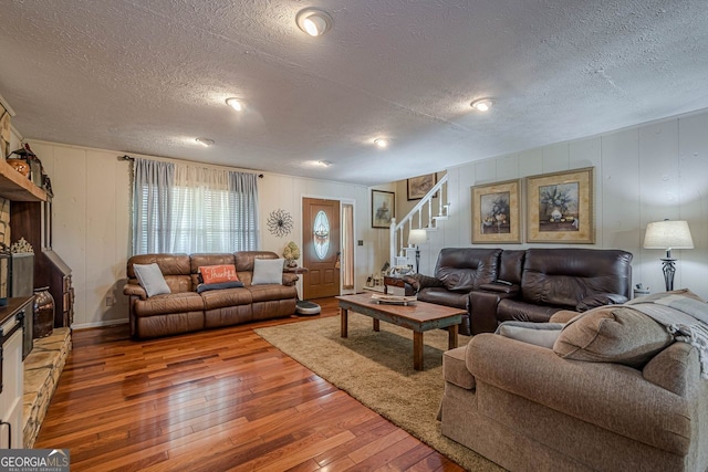 living room featuring a textured ceiling, a fireplace, and hardwood / wood-style floors