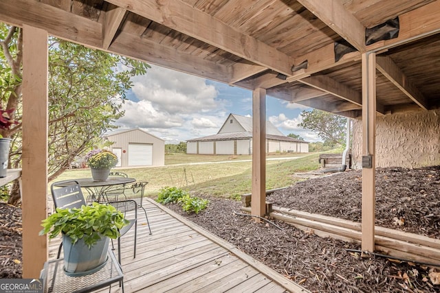 deck with a garage, a yard, and an outbuilding