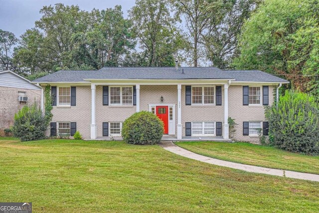 raised ranch with a front yard and a wall mounted AC