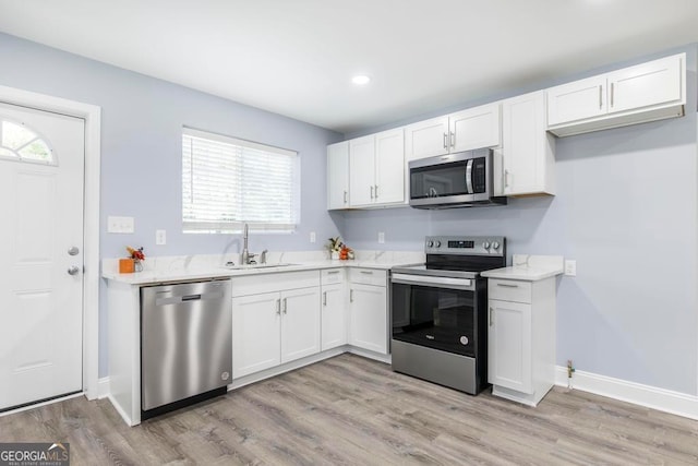 kitchen with light hardwood / wood-style floors, white cabinetry, and stainless steel appliances