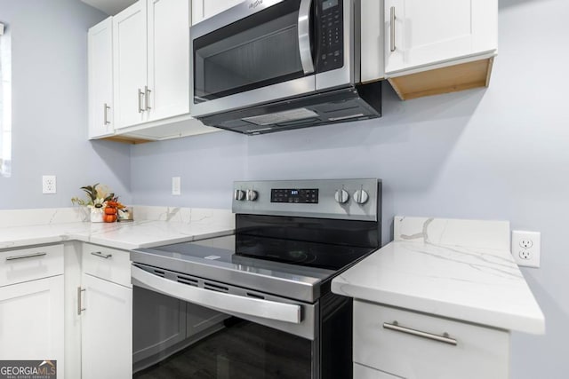 kitchen featuring light stone countertops, stainless steel appliances, white cabinetry, and hardwood / wood-style floors