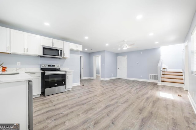 kitchen with light wood-type flooring, white cabinetry, ceiling fan, and appliances with stainless steel finishes