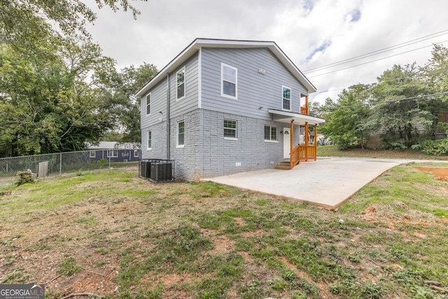 rear view of property featuring cooling unit, a lawn, and a patio