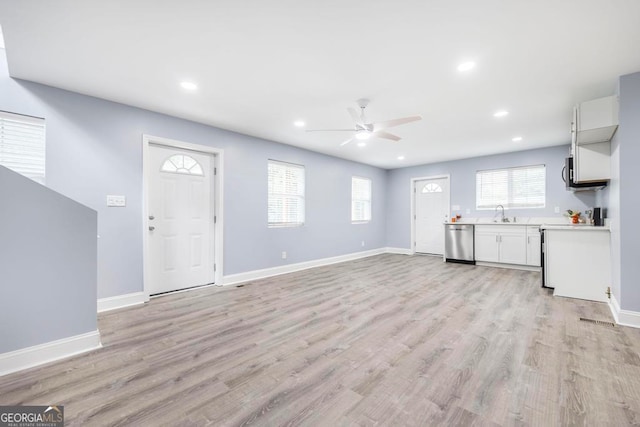 unfurnished living room featuring light wood-type flooring, sink, and ceiling fan