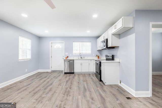 kitchen with light hardwood / wood-style flooring, stainless steel appliances, sink, and white cabinetry