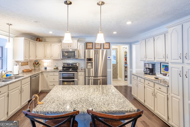 kitchen featuring dark hardwood / wood-style floors, sink, stainless steel appliances, decorative light fixtures, and ornamental molding