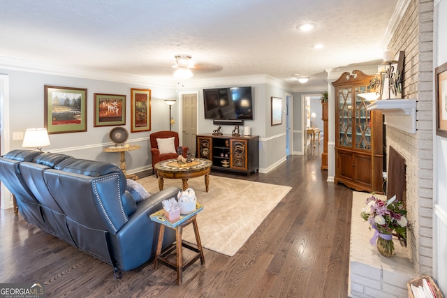 living room with ornamental molding, a brick fireplace, a textured ceiling, and dark wood-type flooring