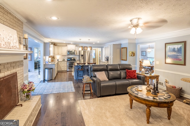 living room with a textured ceiling, crown molding, ceiling fan, and dark wood-type flooring