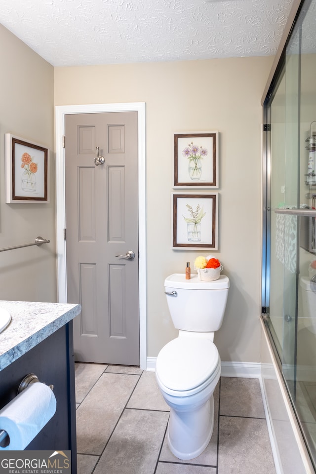 full bathroom featuring tile patterned flooring, a textured ceiling, vanity, enclosed tub / shower combo, and toilet