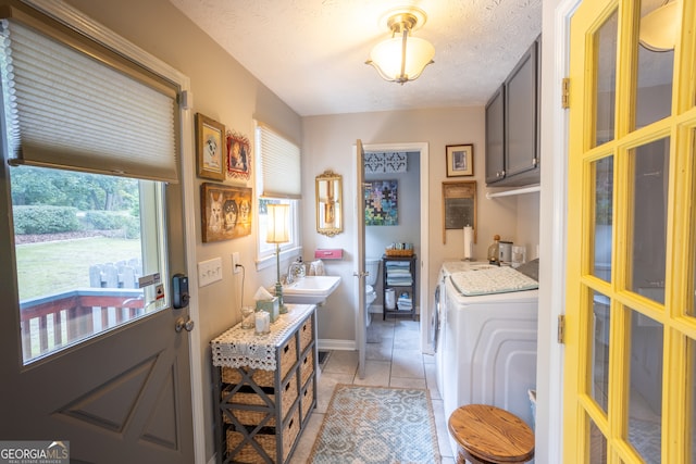 washroom with separate washer and dryer, a textured ceiling, light tile patterned flooring, and a healthy amount of sunlight