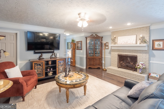 living room with hardwood / wood-style floors, a textured ceiling, a fireplace, and crown molding