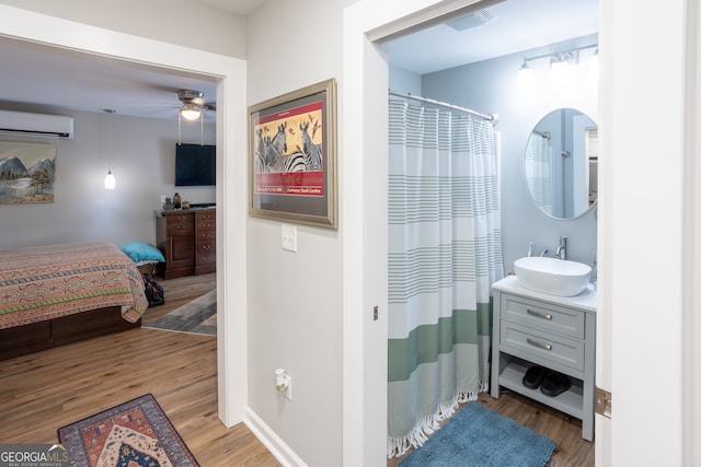 bathroom featuring ceiling fan, vanity, hardwood / wood-style flooring, a shower with curtain, and a wall mounted air conditioner