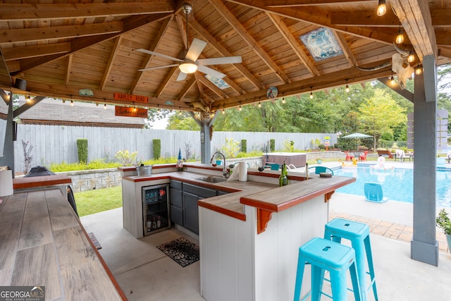 view of patio with an outdoor wet bar, a gazebo, a fenced in pool, and wine cooler