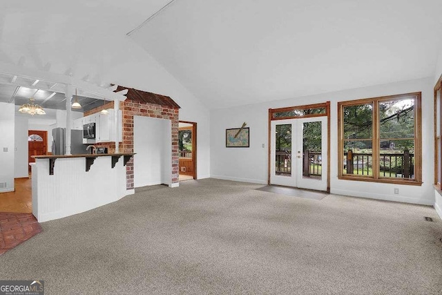 unfurnished living room with light colored carpet, lofted ceiling, and a chandelier