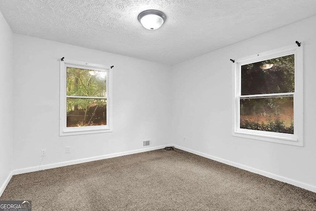 carpeted empty room featuring a textured ceiling