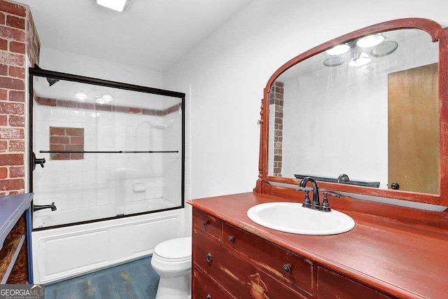 full bathroom with enclosed tub / shower combo, vanity, and toilet