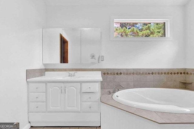 bathroom featuring tiled bath, vanity, and tile patterned flooring