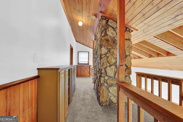 corridor with wooden walls, lofted ceiling, carpet, and wooden ceiling