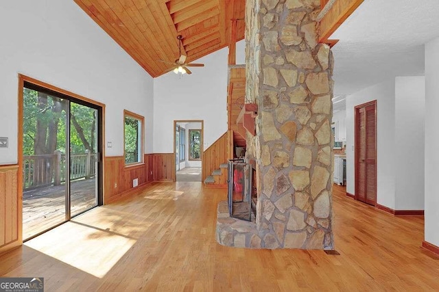 entrance foyer with wooden walls, vaulted ceiling, ceiling fan, and light hardwood / wood-style flooring