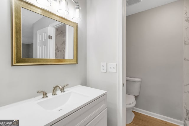 bathroom with hardwood / wood-style floors, vanity, and toilet