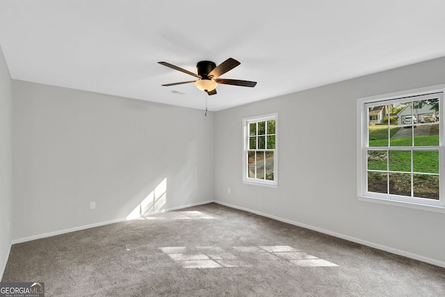 empty room featuring carpet floors, ceiling fan, and a wealth of natural light