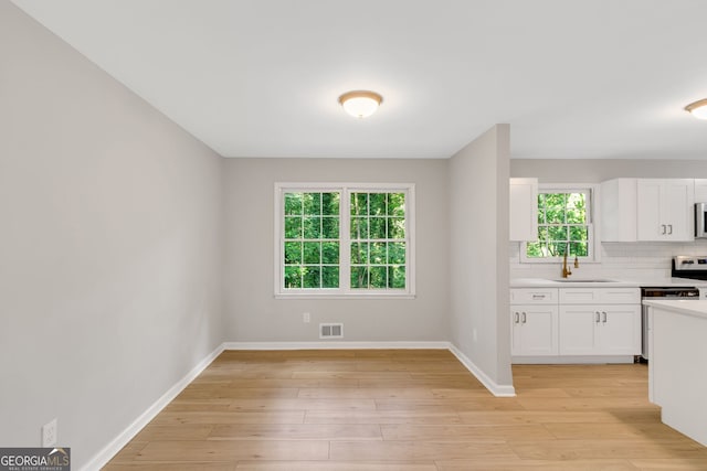 kitchen with decorative backsplash, light wood-type flooring, white cabinetry, and sink